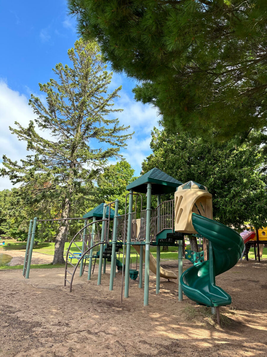 Play structure shaded by pine trees at Hancock Beach